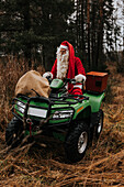 Man wearing Santa costume riding lawn mower