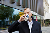 Geschäftsmann trinkt Kaffee zum Mitnehmen im Freien