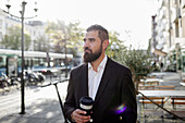 Businessman with takeaway coffee in street