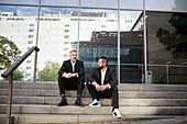 Businessmen sitting on stairs outside office building