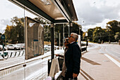Älteres Paar sieht sich an der Bushaltestelle den Fahrplan an
