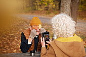 Senior woman photographing her partner in park