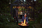 Freunde sitzen am Feuer im Garten