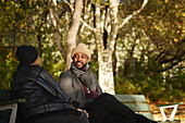 Smiling man talking to friend on bench