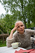Ältere Frau trinkt Kaffee im Garten