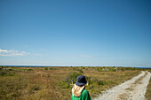 Blond girl on road leading to sea coast