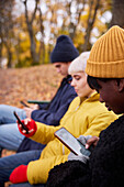 Drei Freunde im Park, die Smartphones benutzen