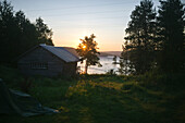 Holzhäuschen am See bei Sonnenuntergang