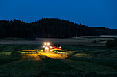 Farm machine working on farm at dusk