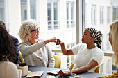 Geschäftsfrauen, die sich im Büro die Fäuste reichen