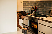 Frau prüft Kekse im Küchenofen