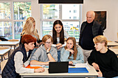Teenager und Lehrerin benutzen Laptop im Klassenzimmer