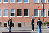 Teenage boys playing basketball in schoolyard