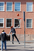 Teenage boys playing basketball in schoolyard