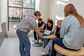 Teenagers using laptop on school corridor