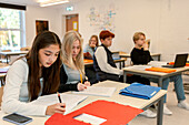 Teenage kids taking notes in classroom