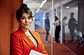 Portrait of smiling businesswoman standing in office corridor