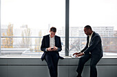 Businessmen using phone and laptop in office