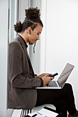 Junger Geschäftsmann mit Laptop und Telefon im Büro