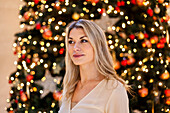 Young woman posing next to christmas tree