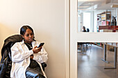Young woman using phone in waiting room