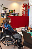 Frau im Rollstuhl arbeitet am Laptop