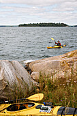 Mann in gelbem Kajak paddelt ans Ufer