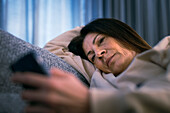Woman lying down and holding smartphone