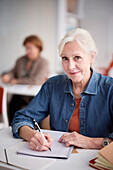 Portrait of mature woman making notes in class