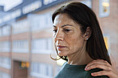 Mature woman standing next to window