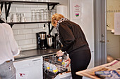 Woman putting dishes into dishwasher