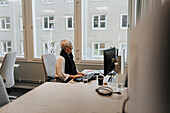 Frau sitzt am Schreibtisch im Büro