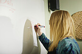 Woman writing on whiteboard at work
