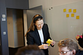 Woman holding post its during business meeting