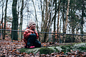 Mädchen kniet auf einem Stein im Wald