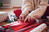 Frauenhände verpacken Weihnachtsgeschenke