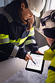 Engineers checking plans on digital tablet