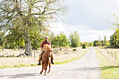 Male farmer riding horse on country road