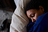 Pensive woman lying in bed at home