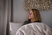 Crying young woman sitting in bed