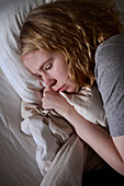Weinende junge Frau im Bett liegend