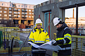 Zwei Ingenieure sehen sich auf einer Baustelle Baupläne an