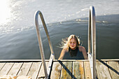 Frau schwimmt in einem See im Winter