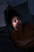 Porträt einer weinenden jungen Frau, die im Bett liegt