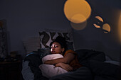 Pensive young woman lying in bed