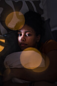 Portrait of pensive young woman lying in bed