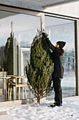 Woman preparing Christmas tree in front of house