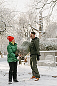 Mann und Frau tragen Weihnachtsbaum im Winter