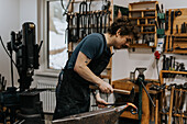 Schmied mit Hammer und Amboss in der Werkstatt