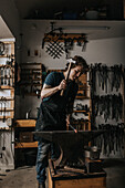 Male blacksmith hammering metal in workshop